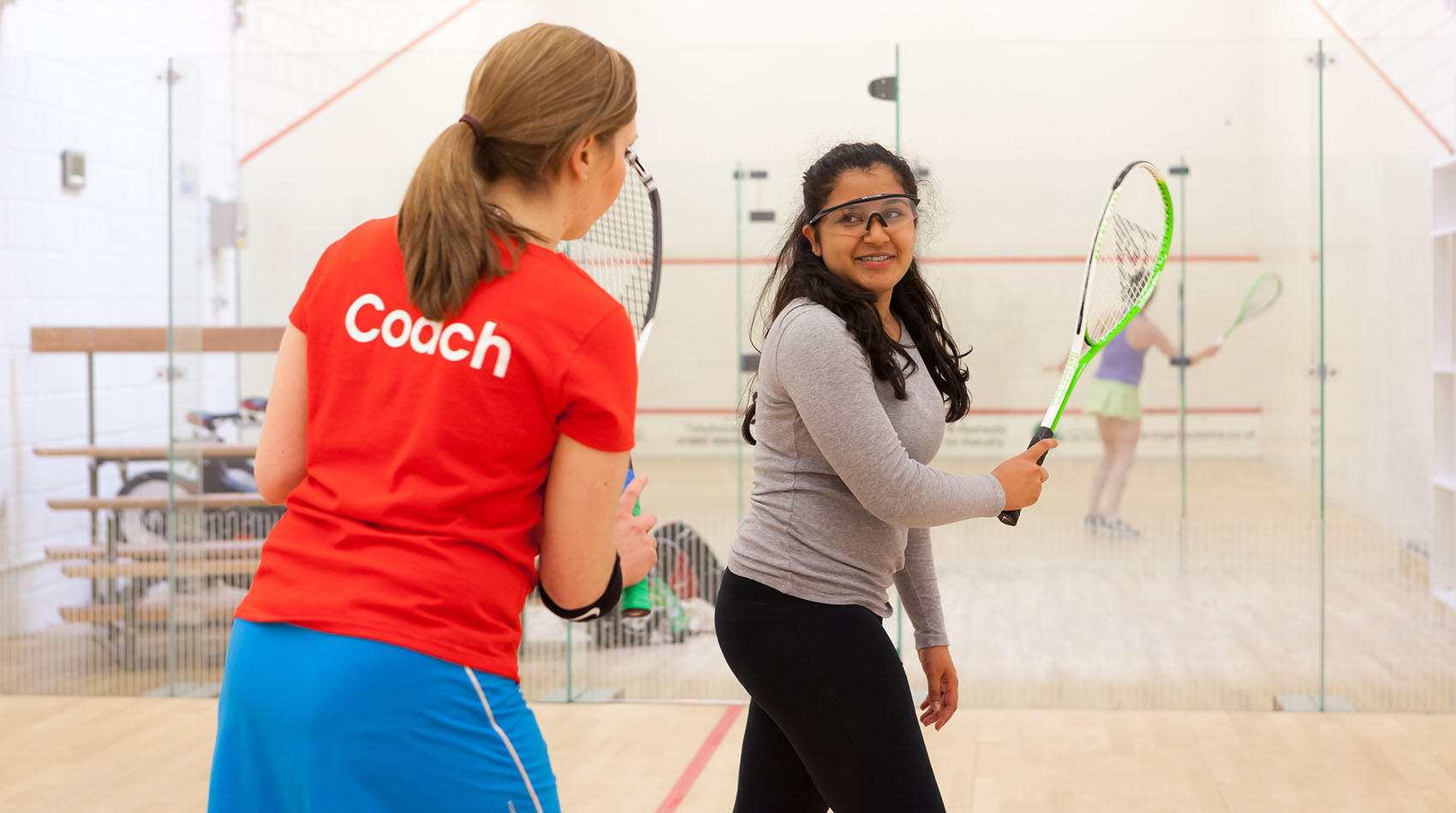 A woman coaching a girl on a squash court